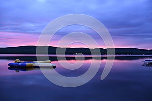 Dramatic scenery of a vibrant, colorful sunset in the cloudy sky over a lake in the evening