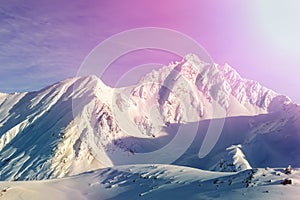 Dramatic scenic pink to purple sunrise in austrian alpine mountain peaks covered with snow layer in winter . Idyllic clear sky on