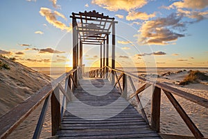 Dramatic sea sunset. The blinding sun hid behind the arch of the wooden bridge