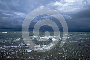 Dramatic seascape in dark colors. Dark sky with clouds over the stormy sea.