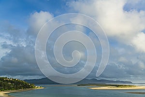 Dramatic sky with evening light illuminating a beautiful scene of homes, sandy beaches, and a calm bay photo