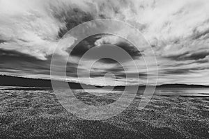 Dramatic sky over beautiful calm water and beach in Gulf of Bothnia. Storsand, High Coast in northern Sweden. Black and white