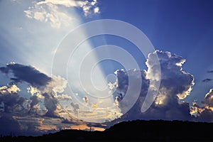 Dramatic sky with sunbeams and dynamic clouds at sunset