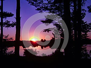 Dramatic sky and sunset in forest over lake water