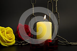 Burning yellow candle, chain and two roses