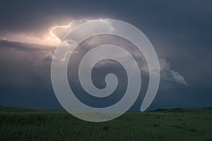 Dramatic storm cloud with lightning bolts curling around the top of the storm over the plains of North Dakota