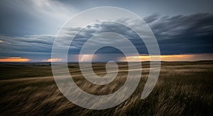 Dramatic storm clouds with sunbeams pierce through a prairie landscape at sunset
