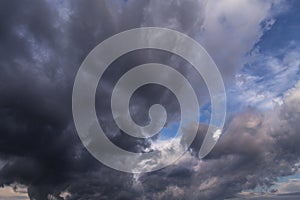 Dramatic storm dark grey cumulus rain clouds against blue sky background texture