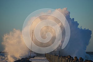 Dramatic, strong waves and foam spray hit the pier in Vorupoer on the North Sea coast of Denmark