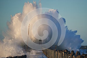 Dramatic, strong waves and foam spray hit the pier in Vorupoer on the North Sea coast of Denmark