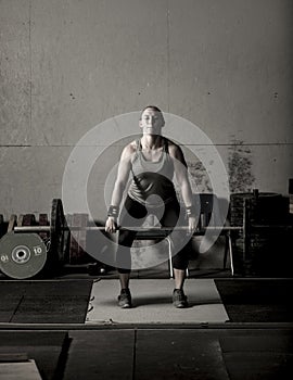 Dramatic subdued color image of strong female weight lifter with barbell