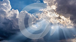 Dramatic sunlight streaming through dark and fluffy clouds in blue sky