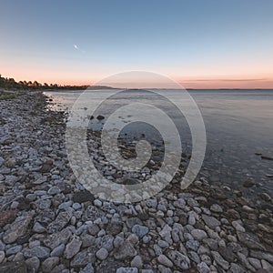 dramatic sunrise over the baltic sea with rocky beach and trees