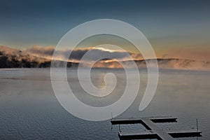 Dramatic sunrise over Deep Creek Lake with an empty dock. Maryland, USA.