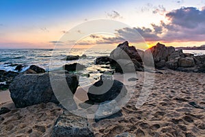 Waves crashing rocks on sandy beach. beautiful cloudscape above the horizon