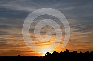 Dramatic sunset in Bavaria. The sky is full of clouds. The colors change from red to blue. At the bottom the shadow of a small