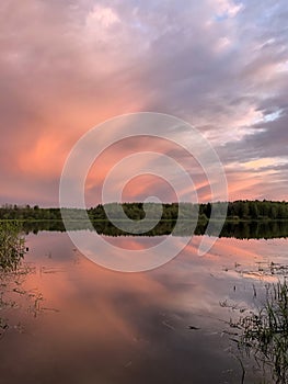 Dramatic sunset clouds over lake and trees - stock photo
