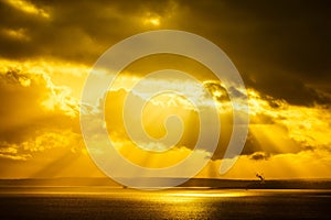 A dramatic sunset through the clouds over the ocean with rays of light