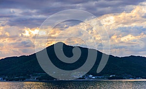 Dramatic sunset clouds over small coastal village and mountain