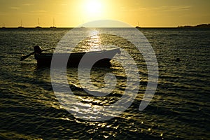 Dramatic sunset colours; beautiful sunset on a beach. Sun reflection in the water, with a fishing boat silhouette