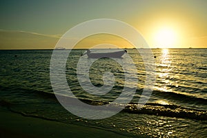 Dramatic sunset colours; beautiful sunset on a beach. Sun reflection in the water, with a fishing boat silhouette