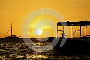 Dramatic sunset colours; beautiful sunset on a beach. Sun reflection in the water, with a fishing boat silhouette