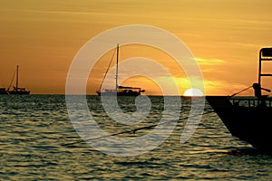 Dramatic sunset colours; beautiful sunset on a beach. Sun reflection in the water, with a fishing boat silhouette