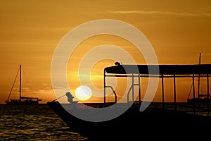 Dramatic sunset colours; beautiful sunset on a beach. Sun reflection in the water, with a fishing boat silhouette