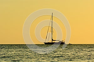 Dramatic sunset colours; beautiful sunset on a beach. Sun reflection in the water, with a fishing boat silhouette