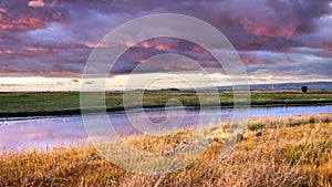 Dramatic sunset landscape with storm clouds reflected in the restored wetlands of South San Francisco Bay Area; Mountain View,