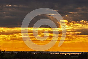 Dramatic sunset like fire in the sky with golden clouds and beams of the sun. Beautiful abstract colorful background. Selective