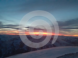 Dramatic sunset in the mountain. Cloudy sky at sunset. High mountain snowy landscape