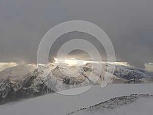 Dramatic sunset in the mountain. Cloudy sky at sunset. High mountain snowy landscape