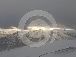 Dramatic sunset in the mountain. Cloudy sky at sunset. High mountain snowy landscape