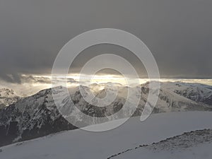 Dramatic sunset in the mountain. Cloudy sky at sunset. High mountain snowy landscape