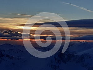 Dramatic sunset in the mountain. Cloudy sky at sunset. High mountain snowy landscape