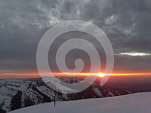 Dramatic sunset in the mountain. Cloudy sky at sunset. High mountain snowy landscape