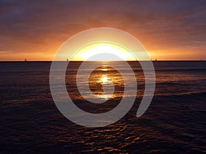 Dramatic Sunset over the clouds and reflecting on the Pacific ocean on the water of Waikiki