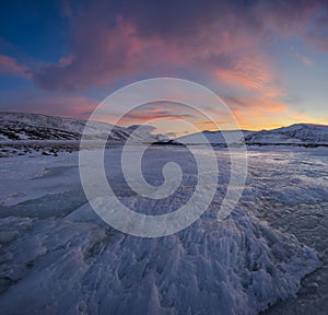 Dramatic sunset over the icy lake in the Arctic tundra. Yamal peninsula.