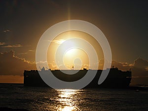 Dramatic Sunset over Pacific Ocean with Cargo Ship passing through