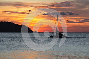 Dramatic Sunset Over Water with Sailboat