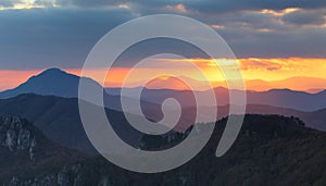 Dramatic sunset rays behind silhouette of of mountain