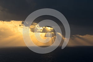 Dramatic sunset rays through a cloudy dark sky over the ocean