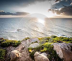 Dramatic sunset rays through a cloudy dark sky over the ocean