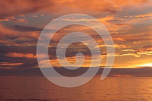 Sunset seascape, orange, blue, yellow, magenta, gold sky reflected in the sea pacific ocean, background photo of sun setting over