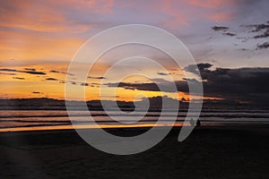 Dramatic sunset sky with clouds. Dramatic sunset over the sea with silhouettes of people by the beach