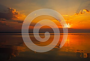 Dramatic sunset sky with clouds over lake.