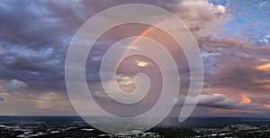 Dramatic sunset sky covered with colorful yellow clouds over dark ground. Panoramic skyscape
