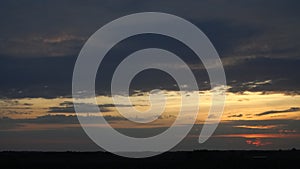 Dramatic Sunset Sky: Dark Grey Clouds with Golden Sunlight