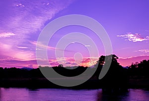 Dramatic sunset in sky and reflect river beautiful colorful tone blue- purple landscape silhouette tree woodland twilight time wit